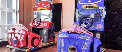 Trois jeux d’arcade de course, intitulés « Voitures rapides », équipés de volants et affichant des numéros de course.