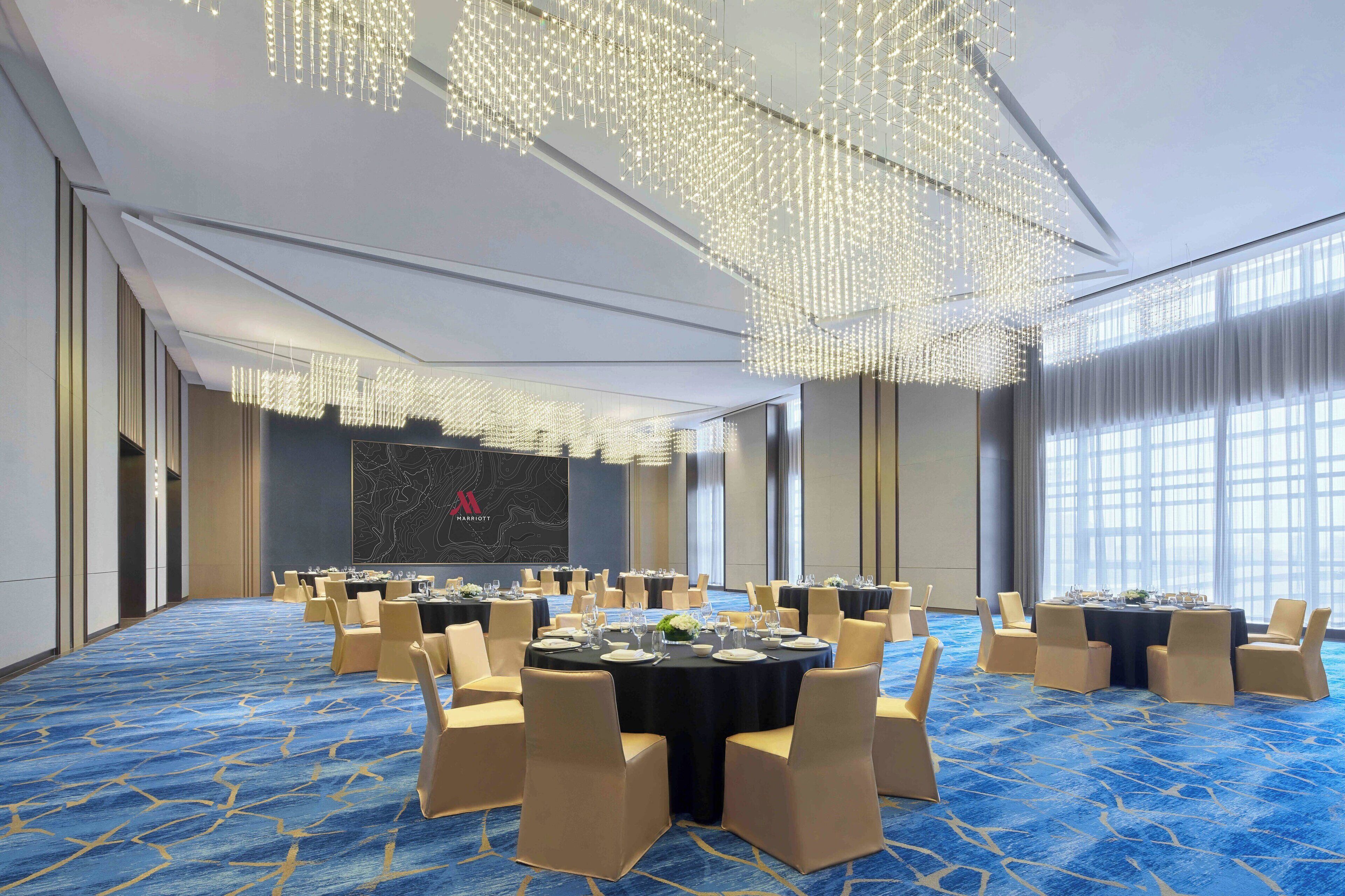 A conference room with round tables, chairs, and a blue carpet.