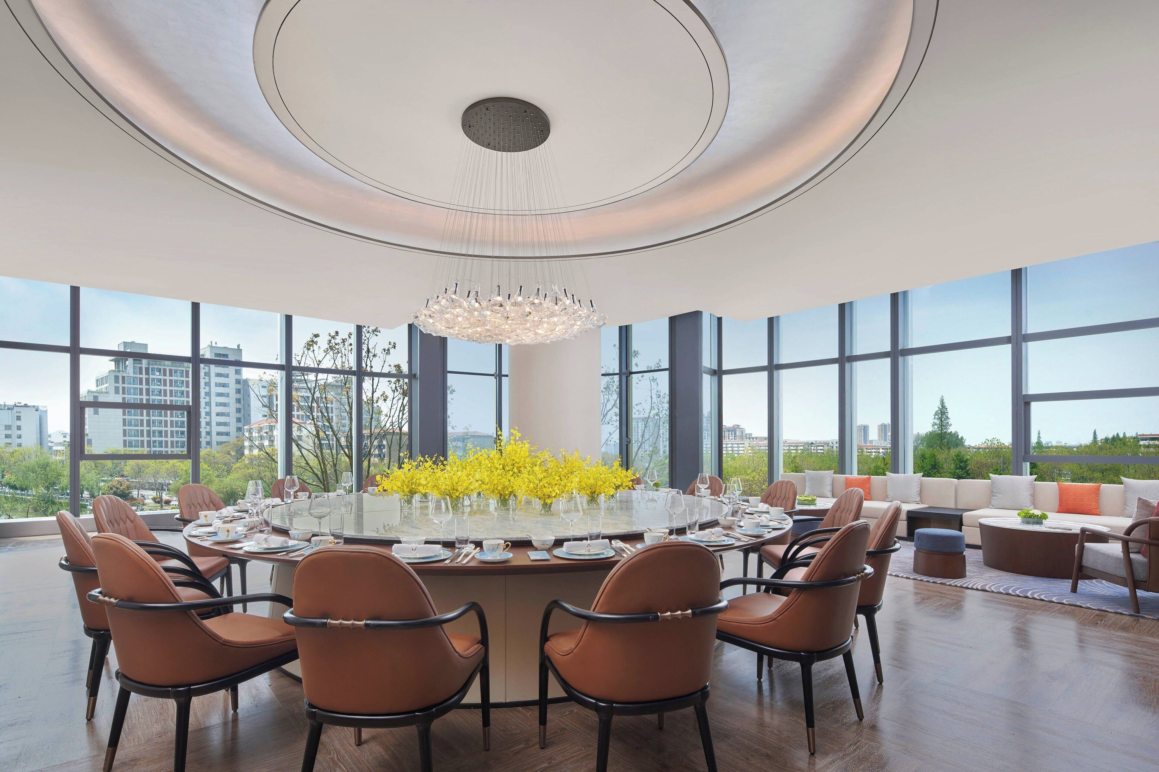 A modern dining area with a round table, chairs, and a chandelier.