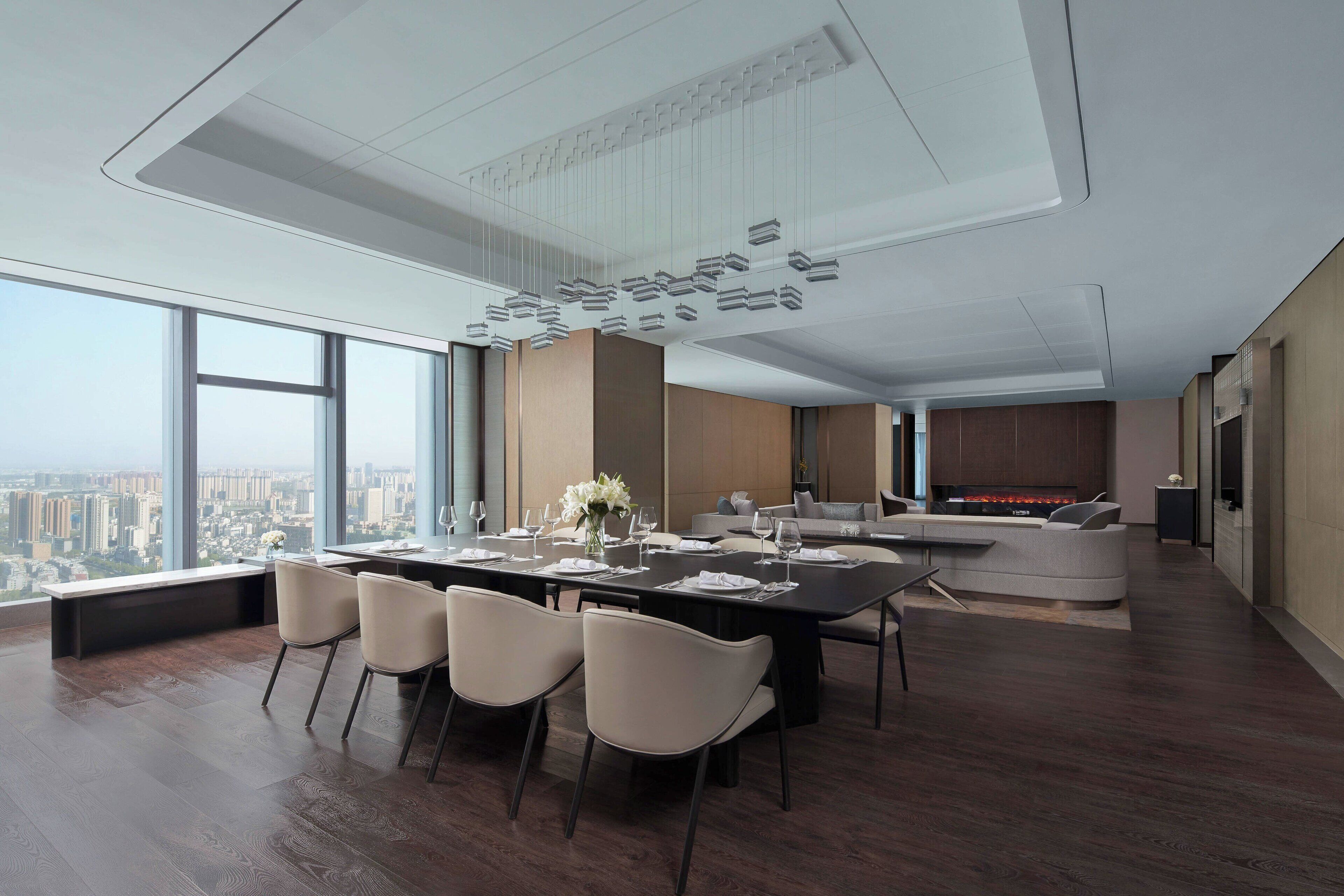A modern dining area with a long table, chairs, and a city view.