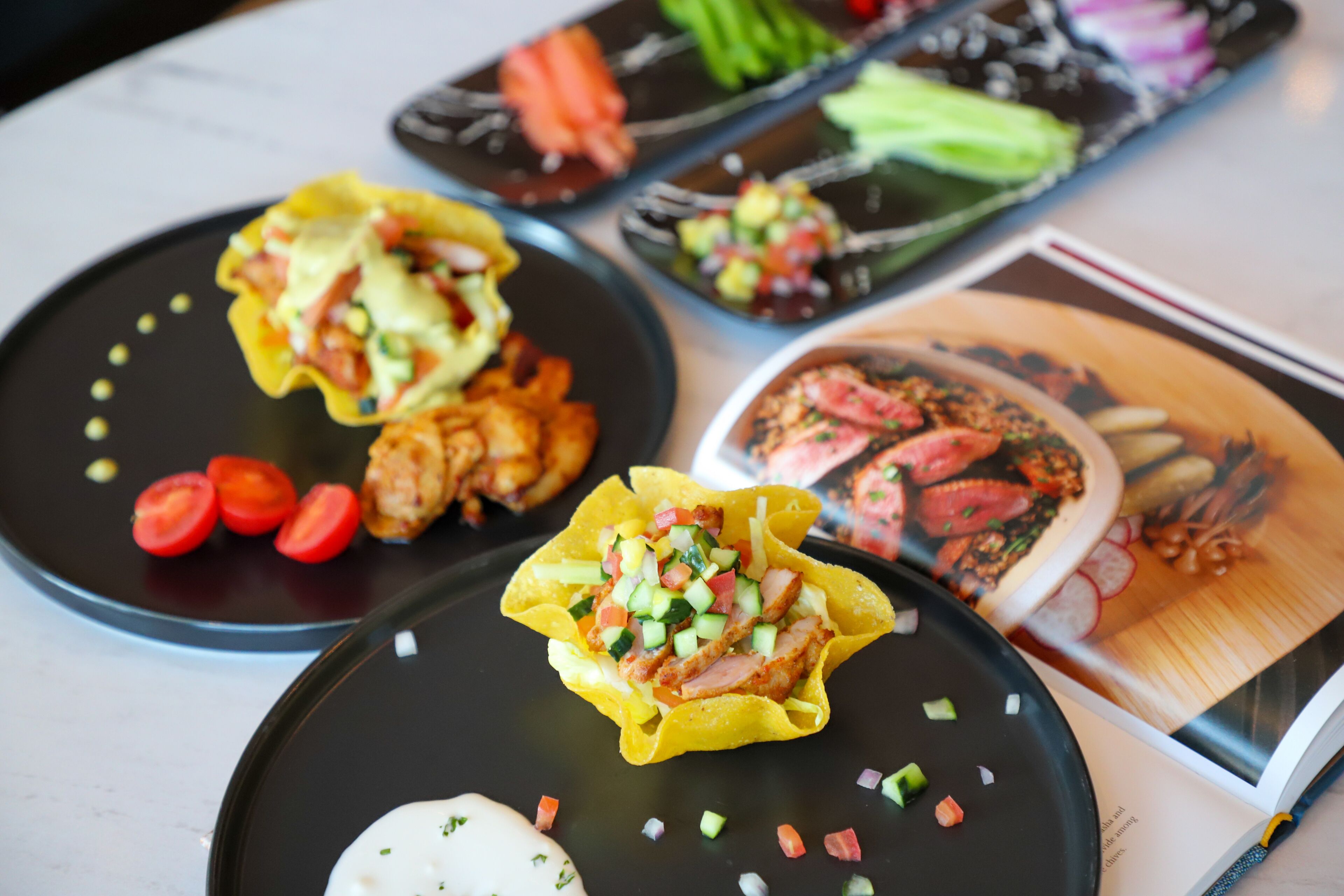 A table with various dishes, including tacos and a dessert.