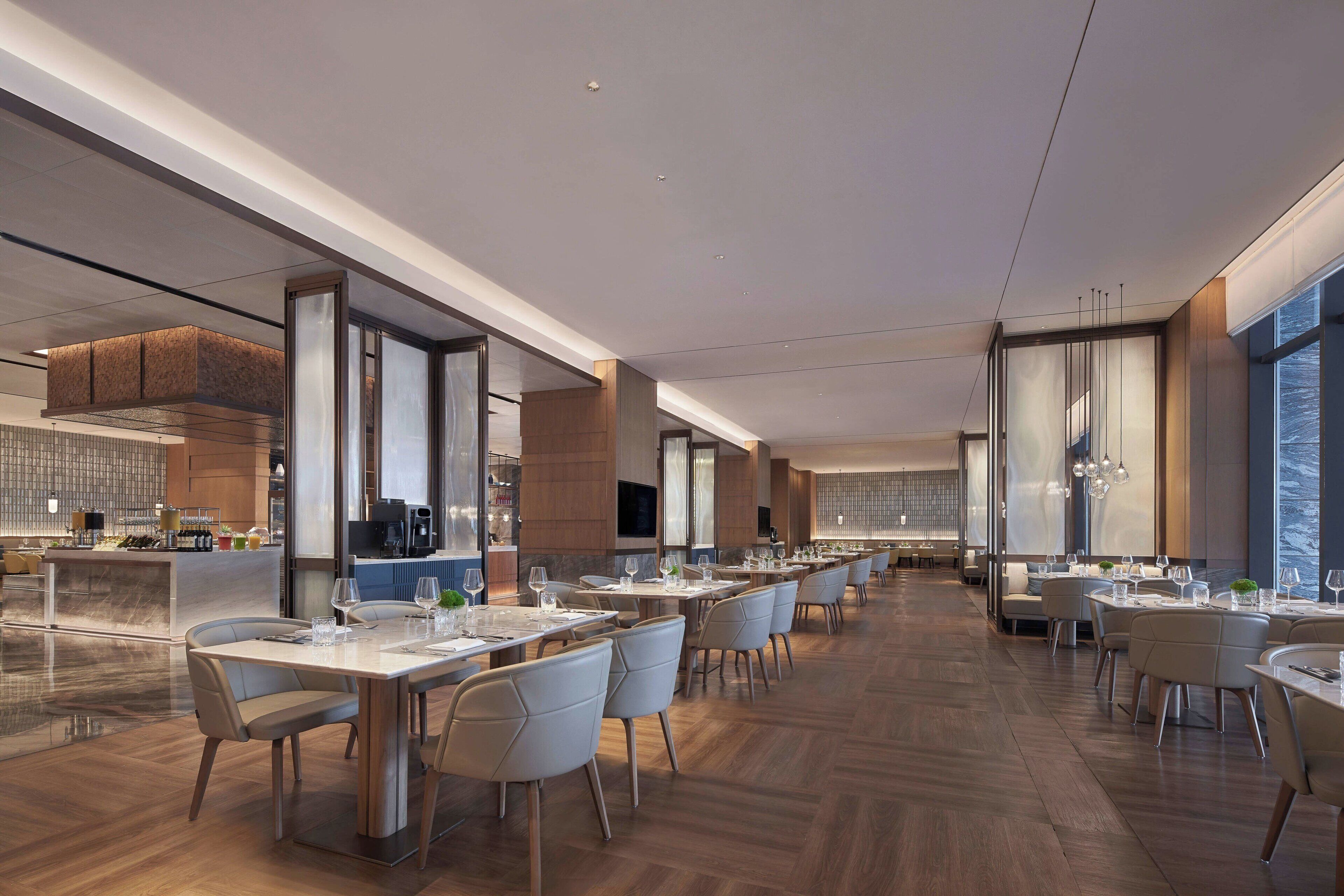 Un restaurante moderno con un amplio comedor, techos altos y grandes ventanales.