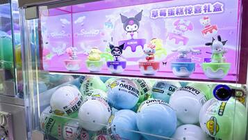 A claw machine filled with colorful balls and a display featuring Hello Kitty and other characters.
