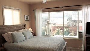 Ein Schlafzimmer mit einem Bett, einem Fenster, einem Fernseher und einem Nachttisch.