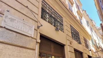 Fachada de edificio con un letrero que dice "Vicolo RM Savele!" y rejas de hierro forjado decorativas.