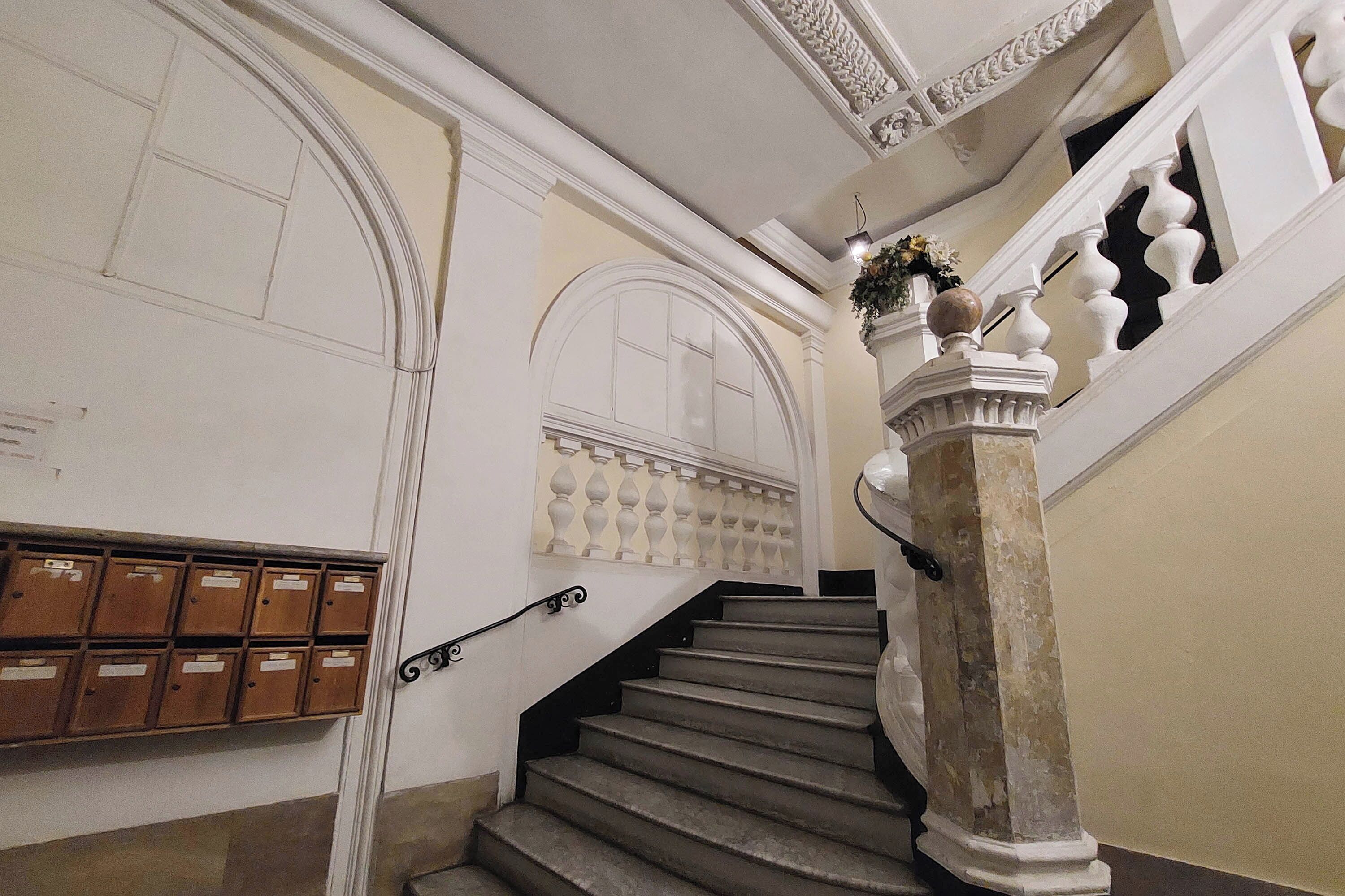 Una imponente escalera con barandales ornamentales y varios buzones en la pared.