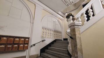 Una imponente escalera con barandales ornamentales y varios buzones en la pared.