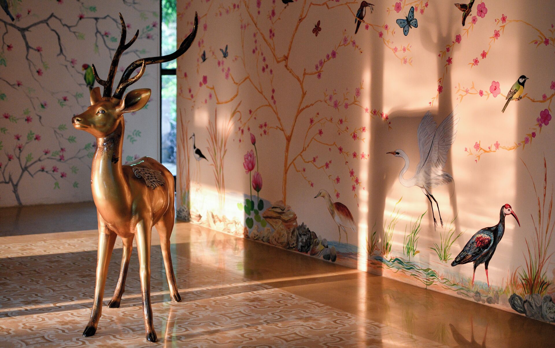 Una figura de cervol en una habitació amb paper pintat floral i un paviment amb motius.