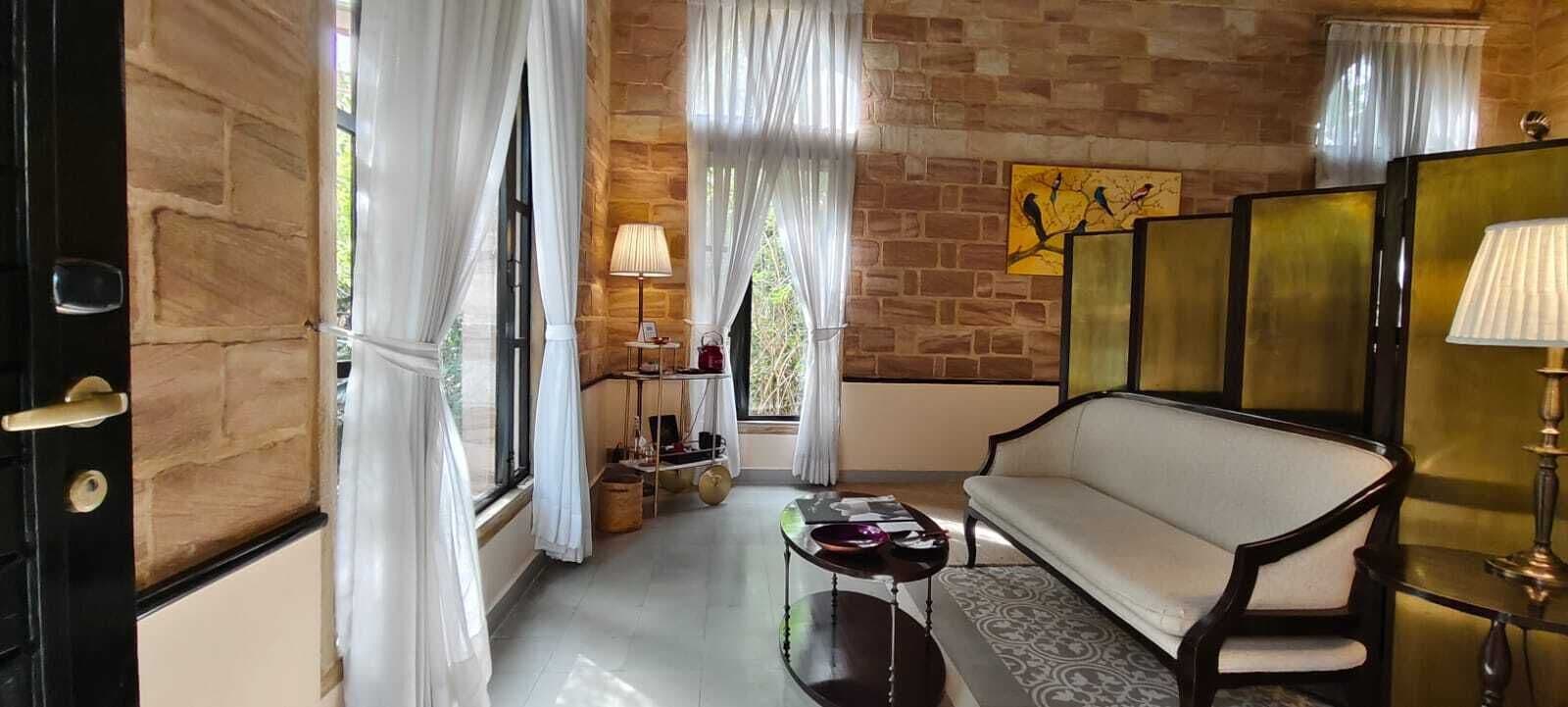 A room with a stone wall, a sofa, a table, and a lamp.