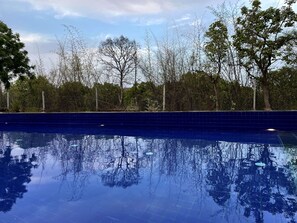 Una piscina al aire libre, sillones reclinables de piscina