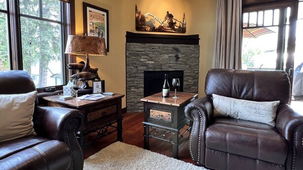 A cozy living room with leather chairs, a fireplace, and a stone accent wall.