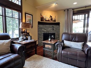 A cozy living room with leather chairs, a fireplace, and a stone accent wall.