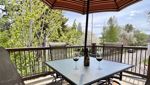 An outdoor patio with a table and chairs, a bottle of wine, and glasses.