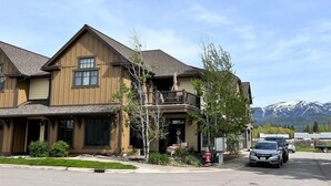 A two-story building with a balcony, a small porch, and a mountain backdrop.