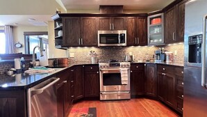 A modern kitchen with dark wooden cabinets, stainless steel appliances, and a central island.