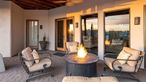 An outdoor patio with a fire pit, two chairs, and a bench.