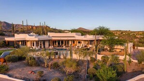 A modern building with a pool, surrounded by desert vegetation.