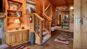 A wooden interior with a fireplace, a staircase, and a dining area.