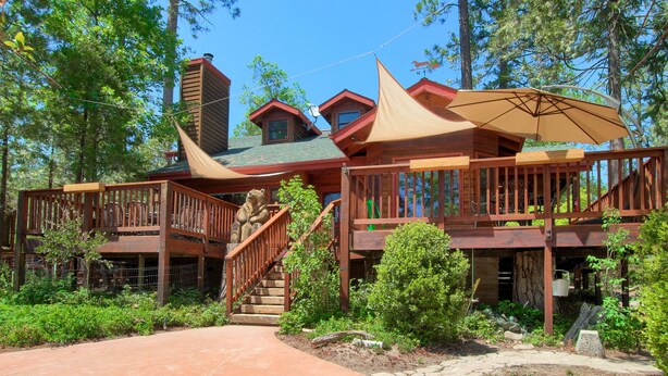 A wooden cabin with a porch, a staircase, and a large umbrella.