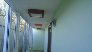Un pasillo estrecho con ventanas amplias a un lado y una puerta al otro.