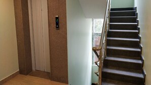 Una escalera con barandilla, una puerta con cerradura digital y suelo cubierto de alfombra.