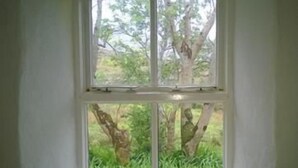 Ein Zimmer mit großem Fenster und Blick auf einen Garten.