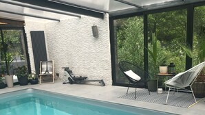 An indoor swimming pool with clear water, surrounded by modern lounge chairs and potted plants. - Villa sur la Route des Châteaux Cathares (Miraval-Cabardes)