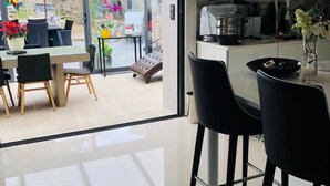 A modern kitchen with a stone wall, a dining area with a glass door leading to an outdoor patio, and a bar area with stools. - Villa sur la Route des Châteaux Cathares (Miraval-Cabardes)