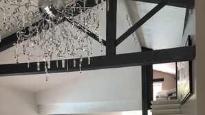 A spacious living area with a modern staircase, a black leather sofa, and a stone wall. - Villa sur la Route des Châteaux Cathares (Miraval-Cabardes)