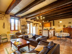 A rustic living room with a leather sofa, wooden coffee table, and a dining area with a table and chairs.