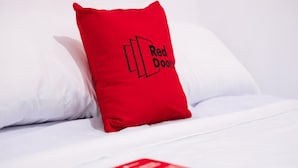 A bed with white bedding and a red pillow with "Red Door" text. - Reddoorz @ Camaman-an Cagayan De Oro City (Cagayan de Oro)