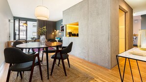 A modern dining area with a round table, dark chairs, and a large pendant light.