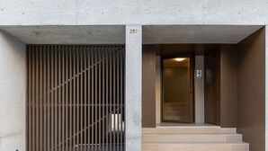 A building entrance with a metal gate, a set of beige steps, and a door with an elevator sign.