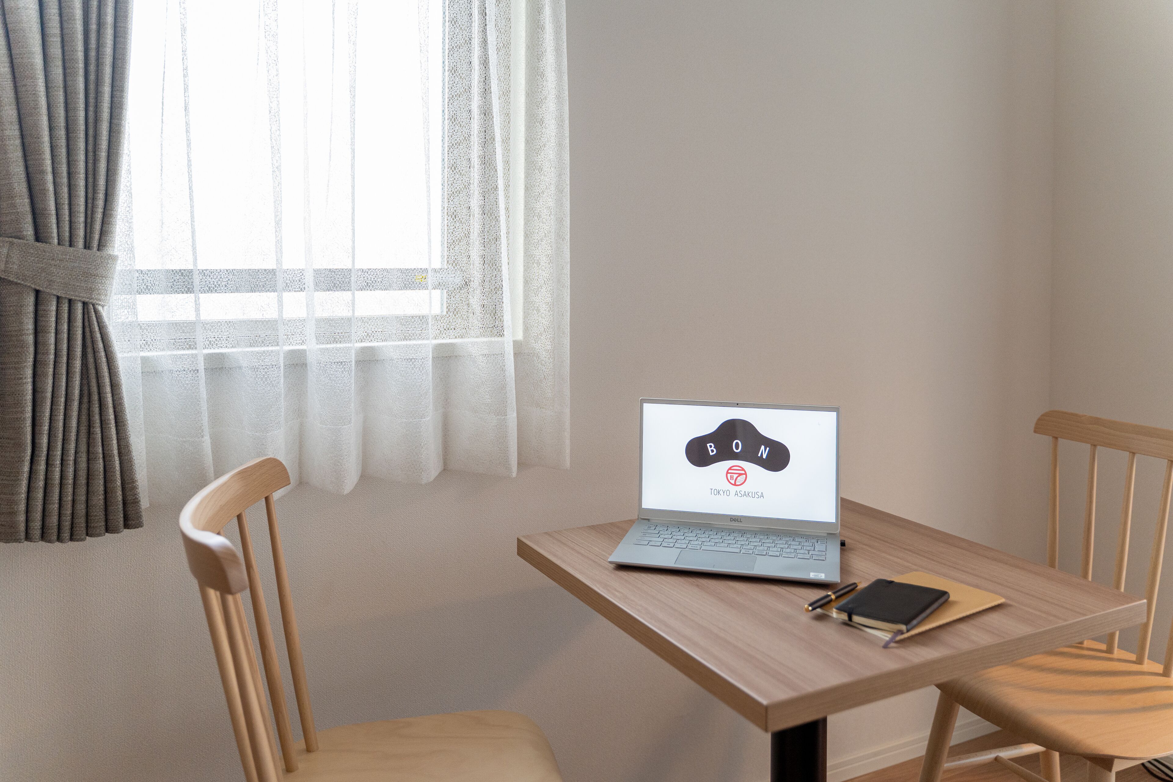 Una computadora portátil sobre una mesa de madera, con un cuaderno, un bolígrafo y un teléfono inteligente.