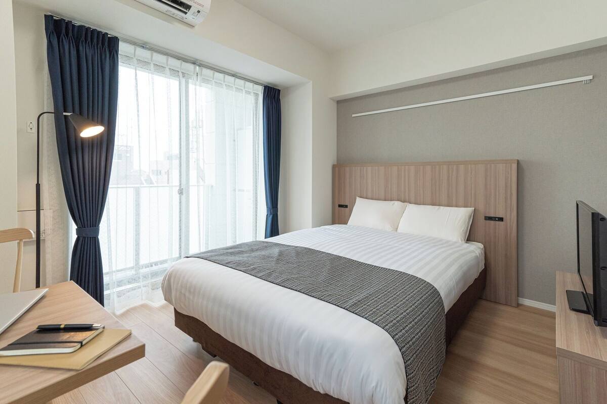 Una habitación de hotel con cama, escritorio, silla y televisión.