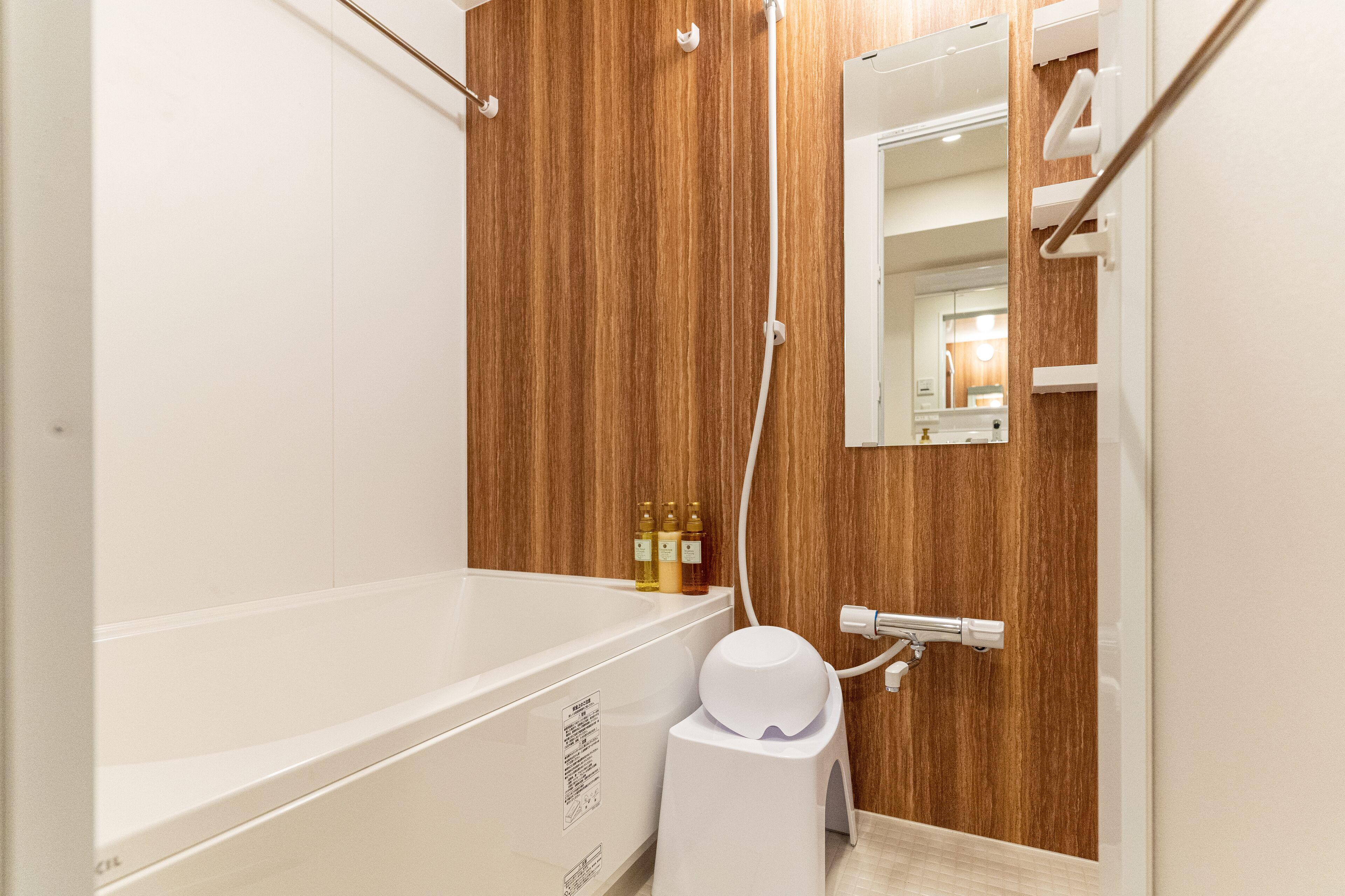 A modern bathroom with a wooden panel wall, a white bathtub, and a mirror above the sink.