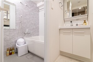Een moderne badkamer met een badkuip, toilet en een wastafel met spiegel.
