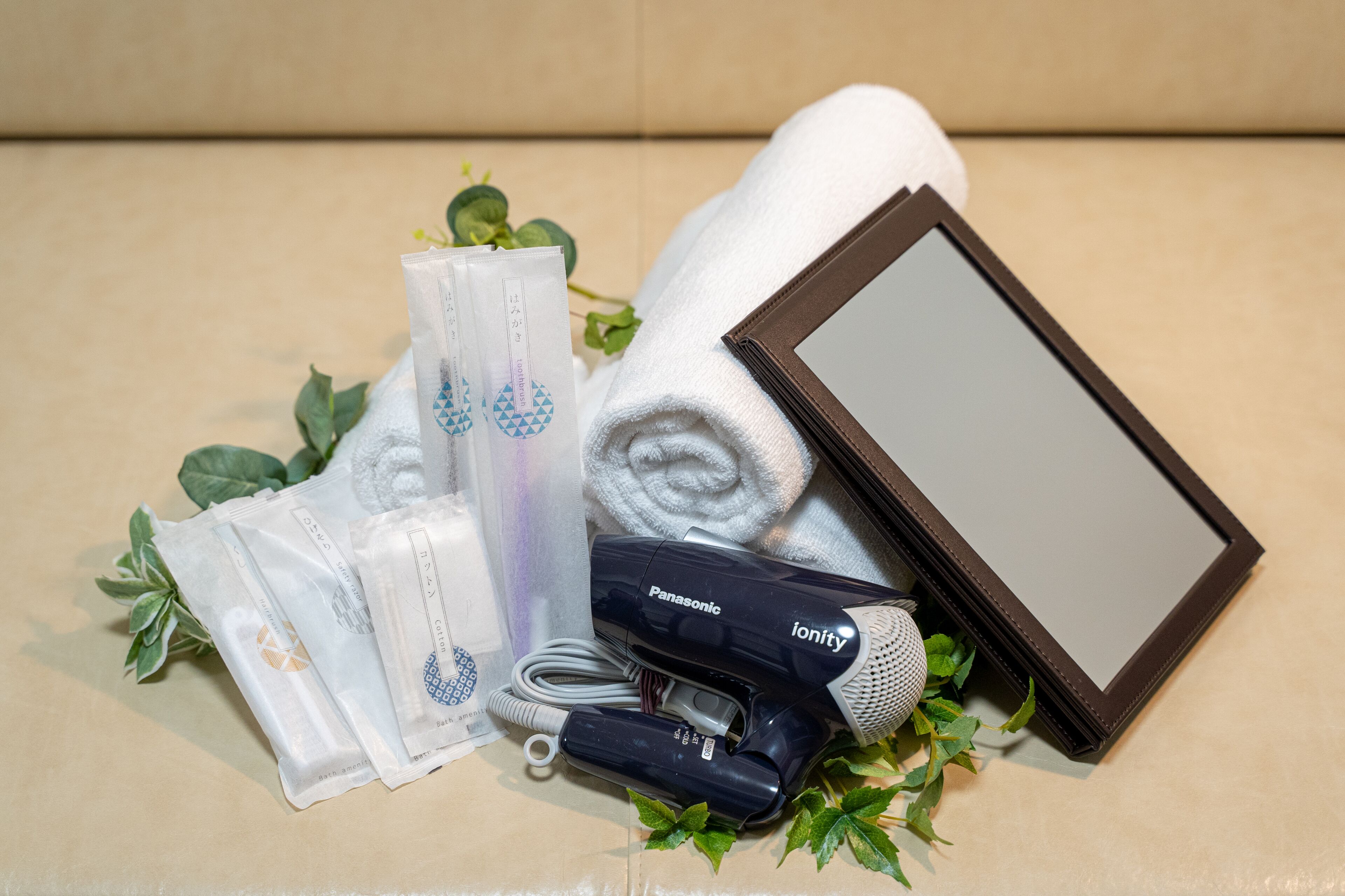 A Panasonic hairdryer, a towel, a mirror, and some toiletries on a beige surface.