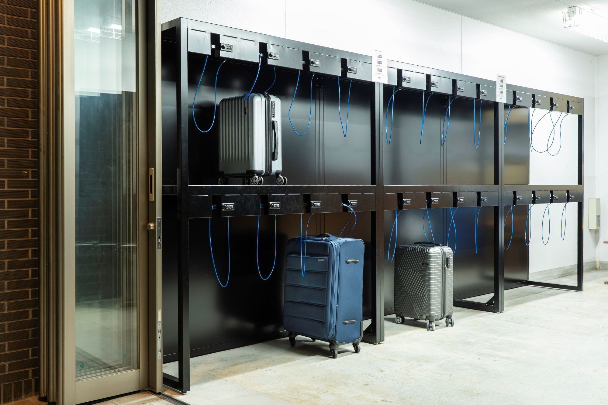 Un espace de stockage de bagages doté de plusieurs casiers et d’une entrée avec une porte en verre.