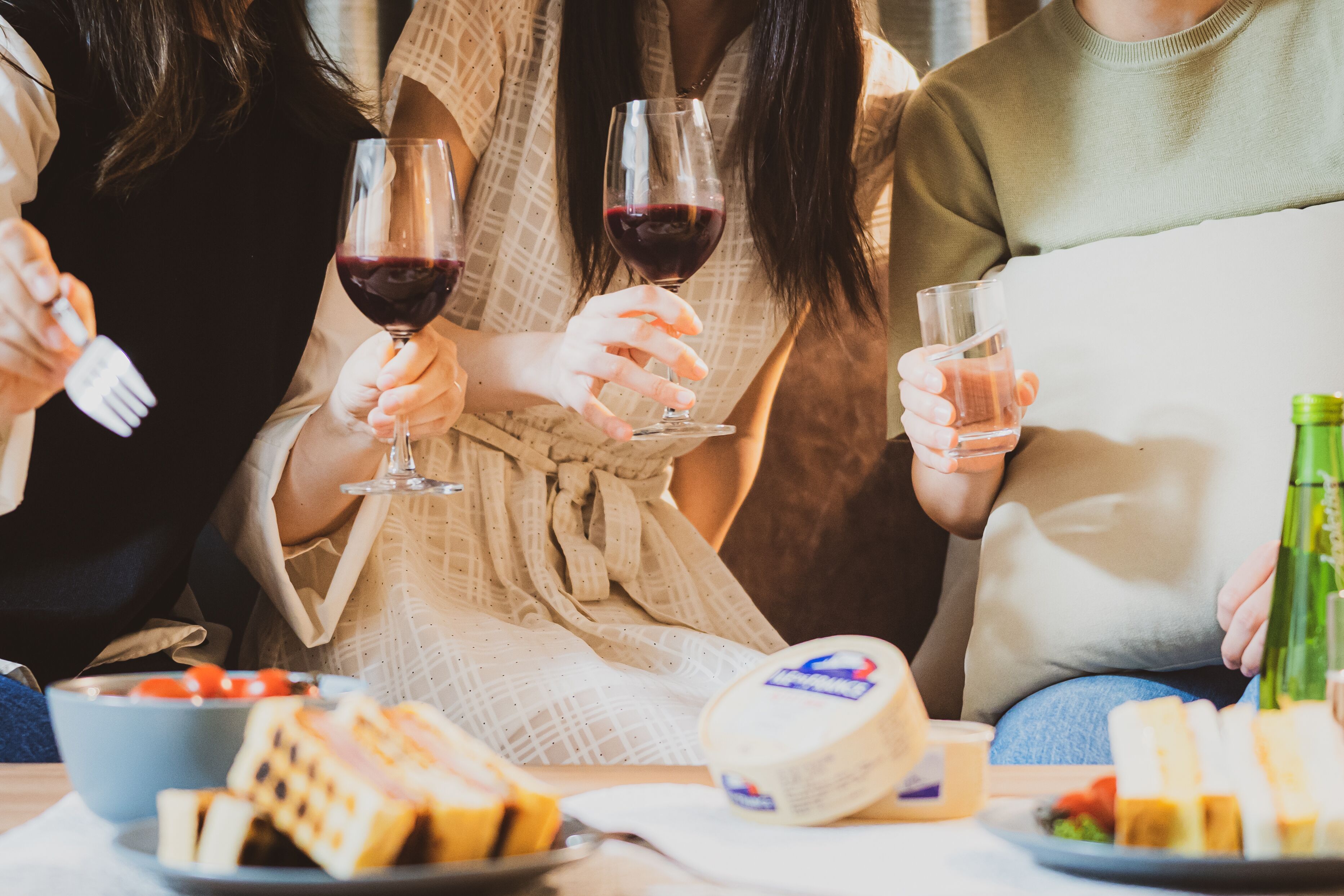 Un grupo de personas sentadas a una mesa con copas de vino, queso y pan.
