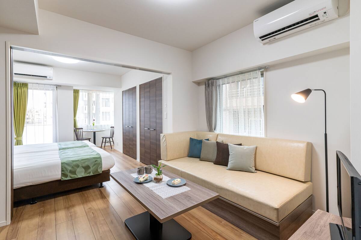 Una habitación de hotel moderna con cama, sofá, mesa de comedor y televisor.