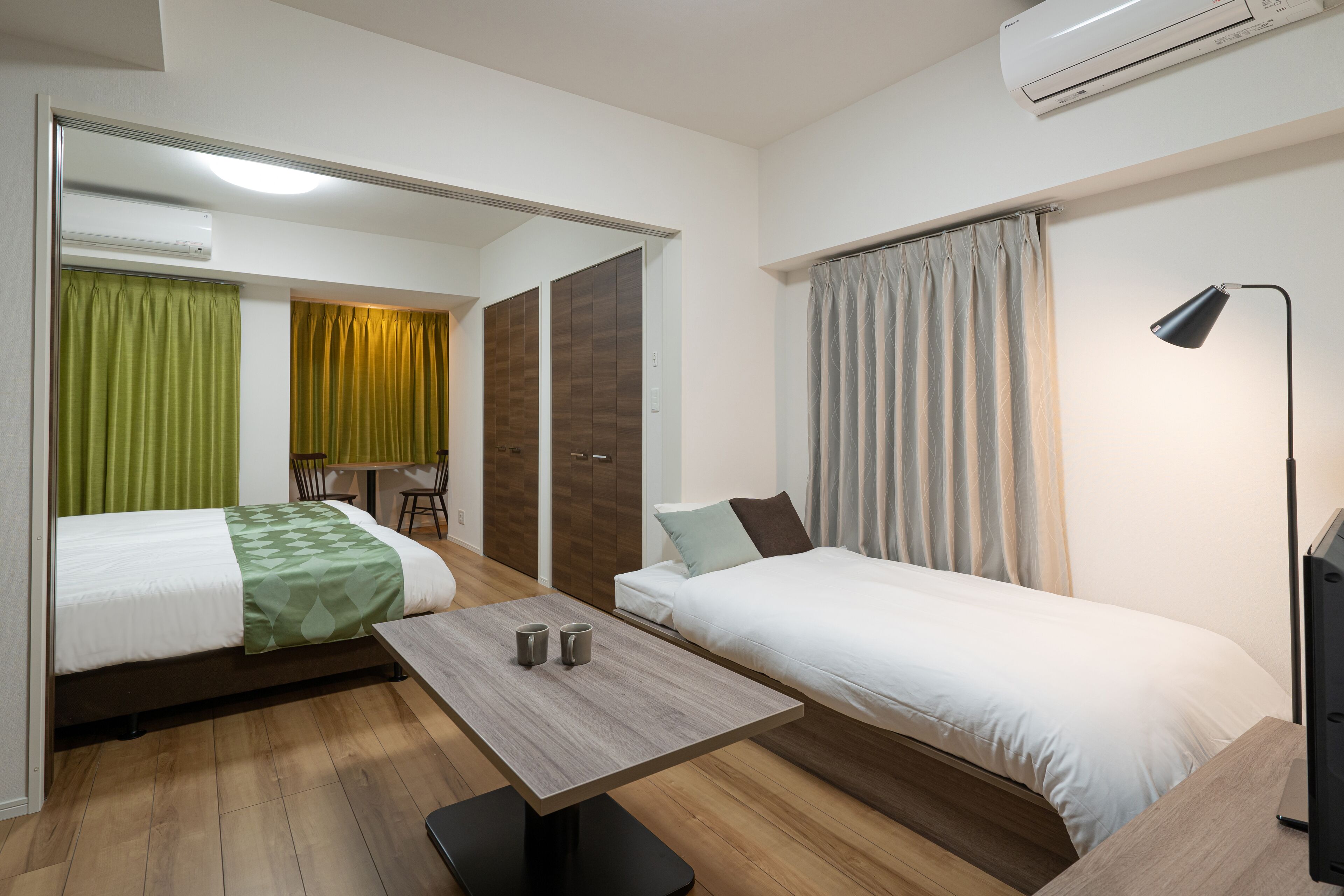 A hotel room with two beds, a table, and a desk.