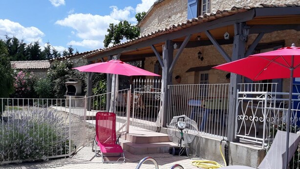 A pool area with a clear blue pool, red umbrellas, and a red lounge chair. - Charming Farmhouse with Private Pool, Garden, and Playground in Peaceful Countryside (Rampieux)