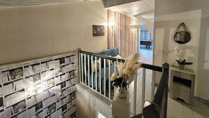A staircase with a bookshelf on the left, a vase with dried flowers on the right, and a billiards table in the background. - Charming Farmhouse with Private Pool, Garden, and Playground in Peaceful Countryside (Rampieux)