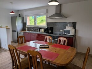 Eine kompakte Küche mit Essbereich, einem Kühlschrank, einer Mikrowelle und einer Kaffeemaschine.
