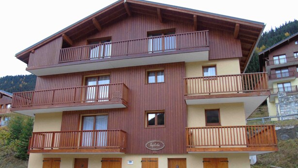 Et hotel med flere etager, træbalkoner, stenvægge og et skilt, der angiver, at det er et familievenligt etablissement.