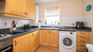 A kitchen with wooden cabinets, a washing machine, a sink, and a window with blinds. - Fantastic 4 bed house with 3 bathrooms in pleasant location (West Bromwich)