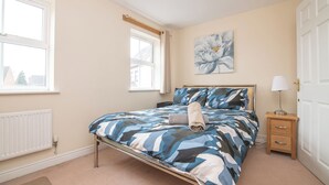 A bedroom with a bed, bedside table, lamp, and a window. - Fantastic 4 bed house with 3 bathrooms in pleasant location (West Bromwich)