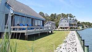 Een pand aan het water met een overdekt terras en een groot huis.