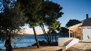 A coastal property with a patio, outdoor seating, and a view of the sea and mountains.